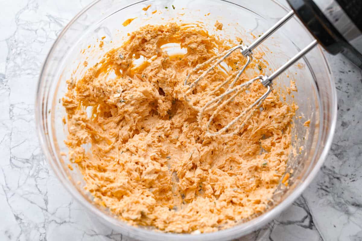 These zesty Buffalo Chicken Pinwheels are an easy snack or appetizer that everyone will devour! A creamy buffalo-flavored spread full of shredded chicken, seasonings, and cheeses all rolled inside of a soft tortilla. Slice into cute pinwheels and enjoy! Second photo of the buffalo cream cheese mixture blended.