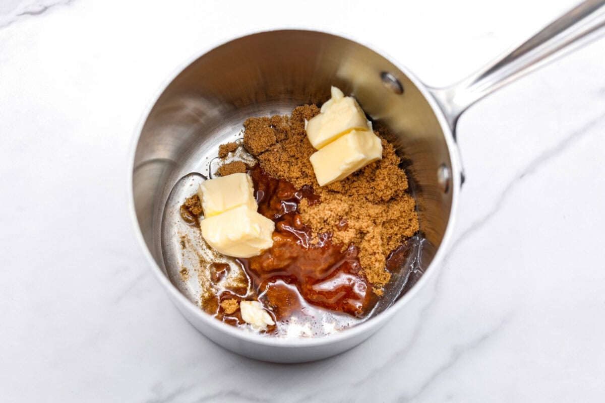 This cornflake brittle crack is crispy, chewy and to die for! With only six ingredients and 8 minutes of prep, you can have this yummy treat ready in no time. This brittle is crunchy cornflakes mixed with a buttery caramel sauce and drizzled in rich dark chocolate. Overhead shot of butter, brown sugar, and corn syrup in a sauce pan.