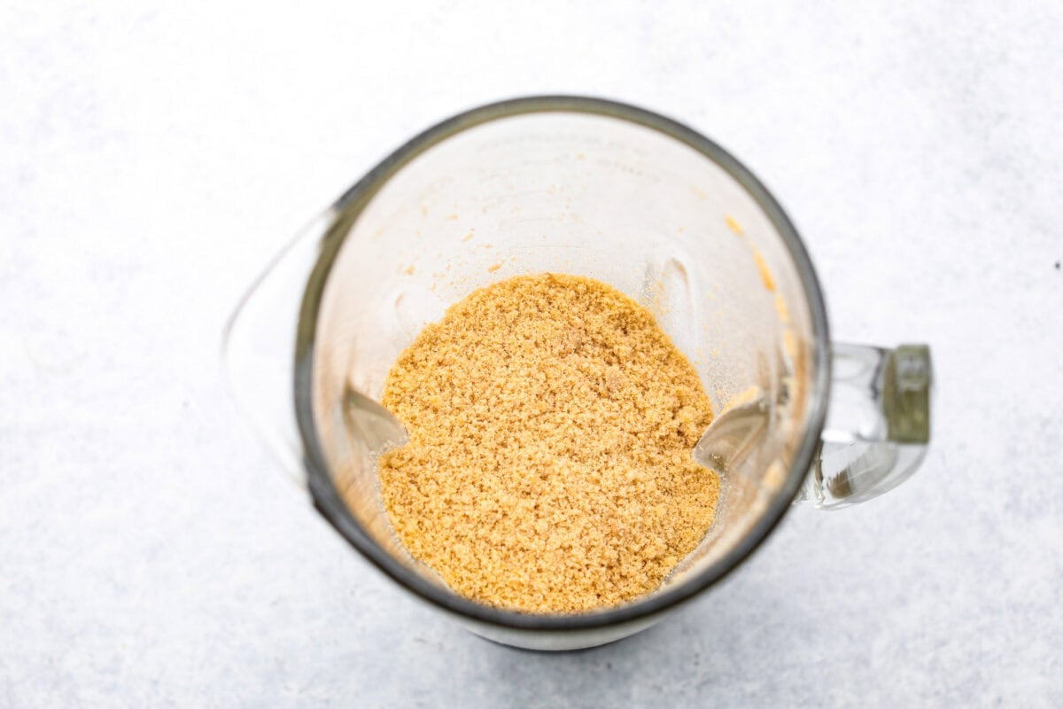 Delicious and addicting, the famous Crack Pie is what made Milk Bar bakery so popular. This copycat recipe is made with a sweet and salty filling tucked inside a crispy oat cookie crust. It’s so good you won’t be able to stop eating it! Overhead shot of oatmeal cookie crumbs in a blender.