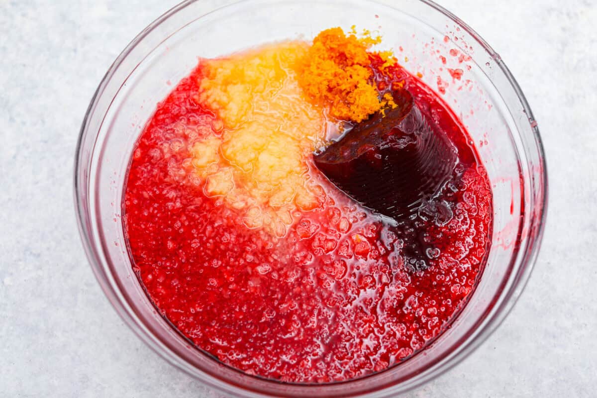 Cranberry Jello Salad is the best combination of tart, tangy, and sweet! It's similar to cranberry sauce but a little sweeter from the jello with undertones of orange and pineapple. Add it to your holiday spread and watch it disappear! Overhead shot of the jello salad ingredients in a mixing bowl.