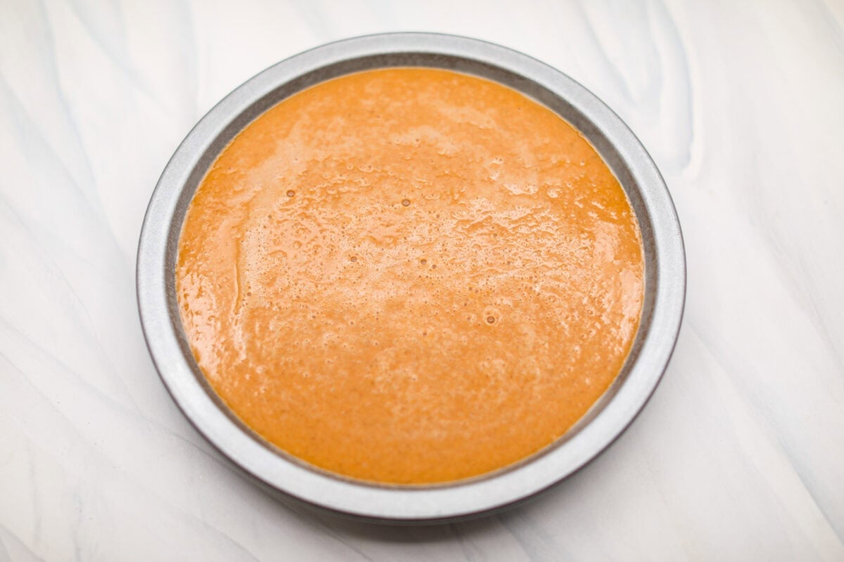 Crustless pumpkin pie has rich spices, creamy pumpkin, and a perfectly smooth texture. The custard holds its shape beautifully. Whether you're keeping things simple or exploring a gluten-free option, this pie gives all the nostalgic vibes of the classic. Overhead shot of pie pan with whisked ingredients inside it.