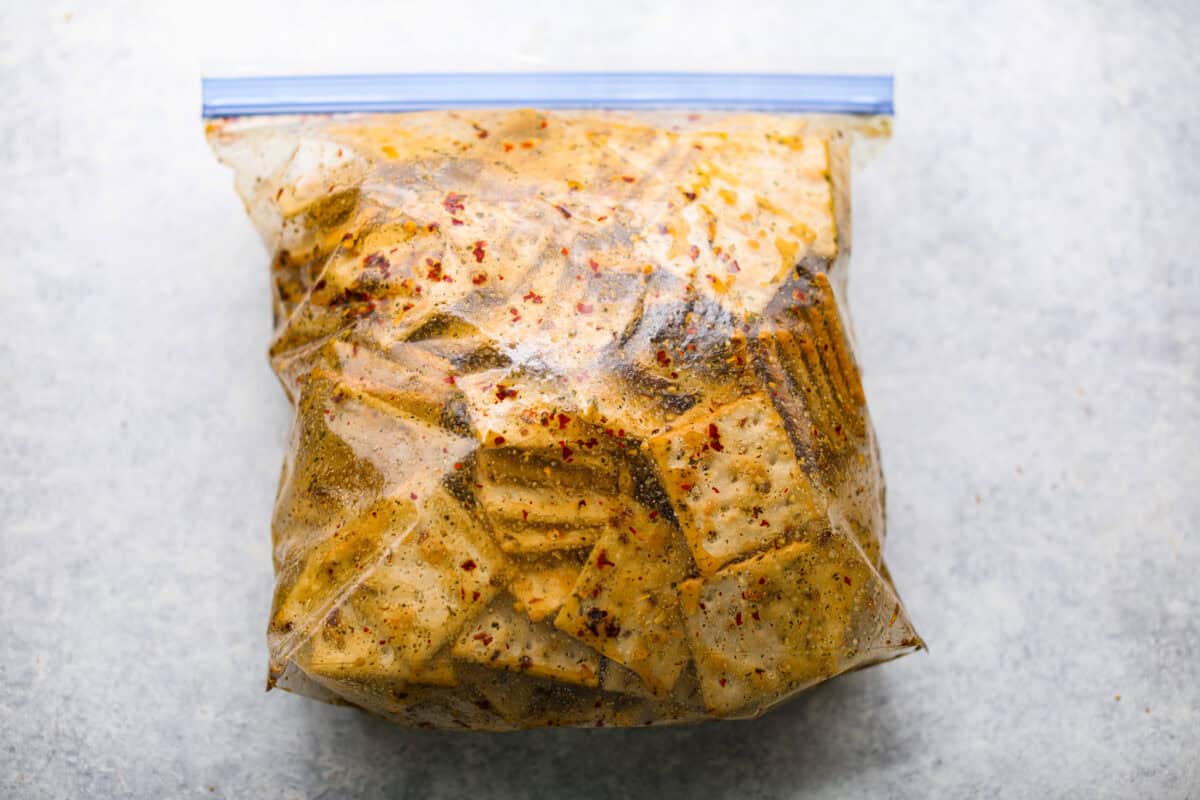 Get the party started with Fire Crackers! In this recipe, saltine crackers are transformed from something ordinary into something extraordinary with a flavorful blend of seasonings. They're easy to make and perfect for snacking on around the holidays (or anytime)! Overhead shot of a ziplock bag with sauce ingredients and saltine crackers.