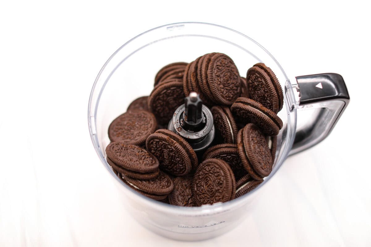German Chocolate Cheesecake is a rich and impressive dessert! It has an Oreo cookie crust, a chocolate cheesecake filling, and a classic German chocolate topping to finish it off! The gooey coconut pecan topping takes this cheesecake to the next level! First photo of Oreo cookies in a food processor.
