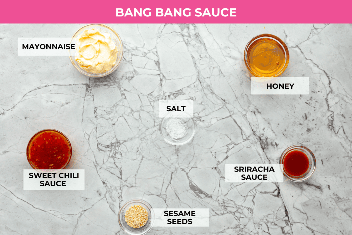Bang Bang Salmon takes salmon filets, smothers them in bang bang sauce that is sweet with a kick, and then baked to perfection. You will love this simple yet oh-so-tasty dinner that can be ready to serve in less than 30 minutes! Overhead shot of labeled sauce ingredients.