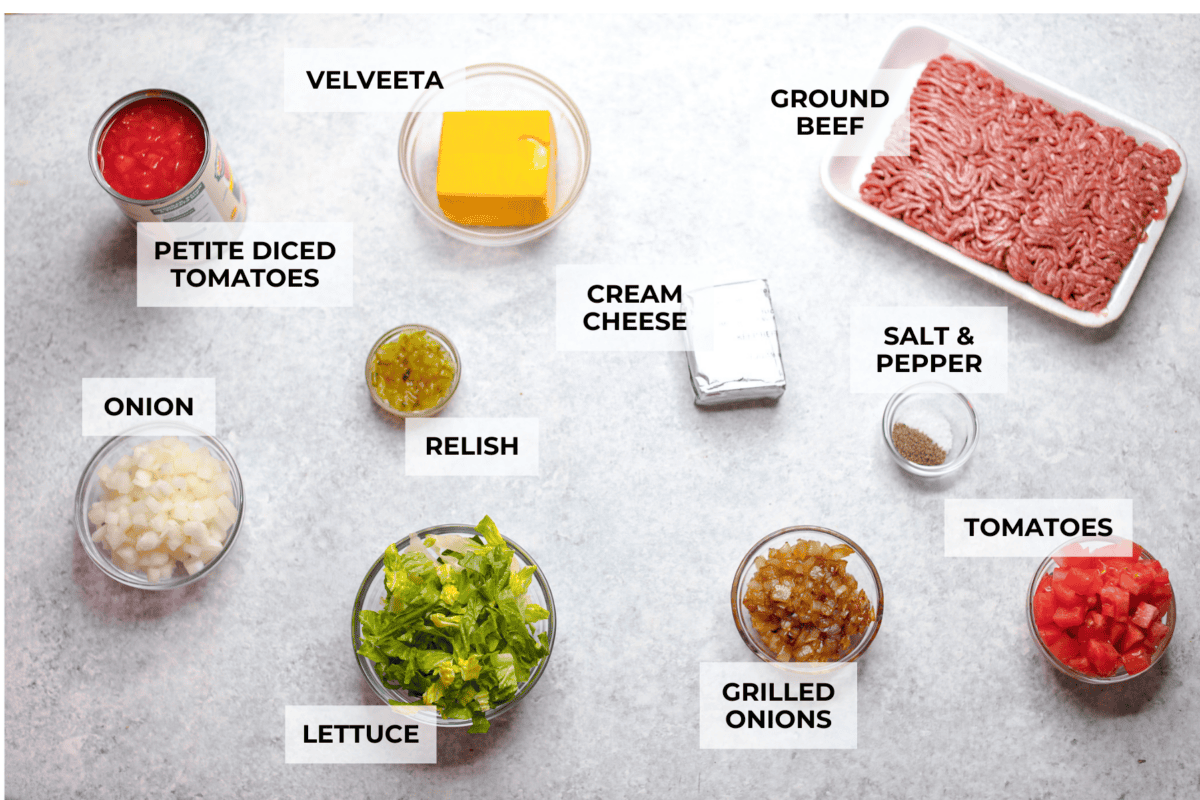Cheeseburger dip is a crowd-pleasing appetizer for potlucks, parties, and get-togethers! This recipe takes delicious cheeseburger ingredients like beef, onion, tomato, relish, and cheese and turns them into a deliciously addicting snack! Overhead shot of labeled ingredients.