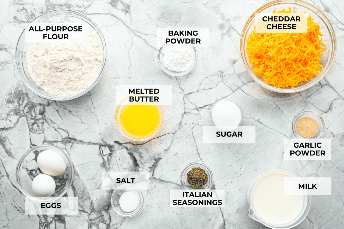 Easy Cheesy Quick Bread is packed with flavor and has a tender, golden crust and soft, moist interior. It's perfect with soup, salad, chili, or on its ownย with a pat of butter. It's simple to make and irresistibly delicious! Overhead shot of labeled ingredients.