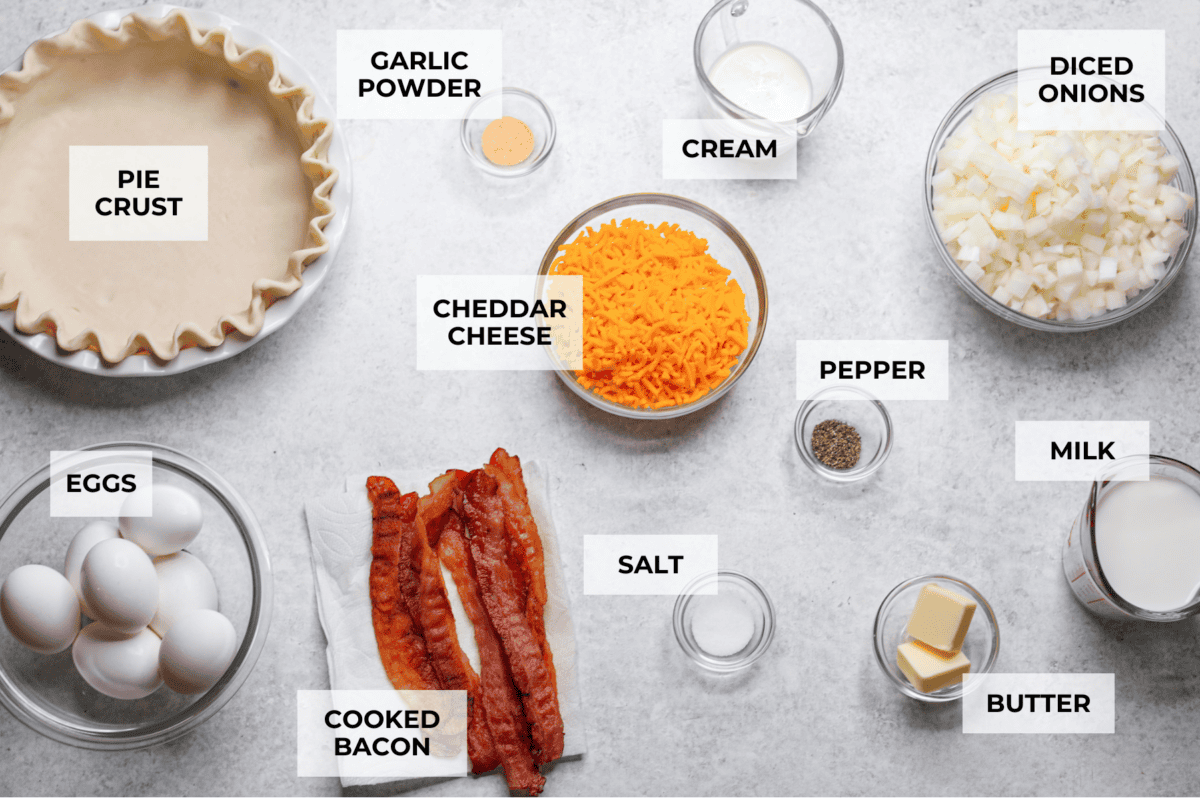 Cowboy Quiche is the ultimate hearty, satisfying breakfast that brings classic comfort to the table. It is filled with smoky bacon, caramelized onions, and cheddar cheese, all baked together in a buttery pie crust. It’s rich, savory, and packed with bold flavor. Overhead shot of labeled ingredients.