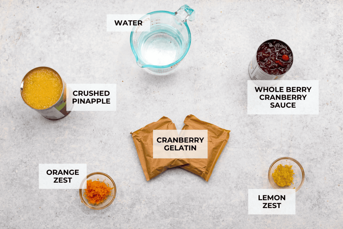 Cranberry Jello Salad is the best combination of tart, tangy, and sweet! It's similar to cranberry sauce but a little sweeter from the jello with undertones of orange and pineapple. Add it to your holiday spread and watch it disappear! Overhead shot of labeled ingredients.