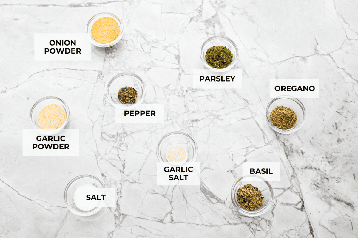 Homemade garlic herb seasoning is a great mix to have on hand. It has multiple uses, is full of flavor, and is adjustable to suit your taste preferences. It has the perfect mix of herbaceous dried herbs, garlic, onion powder, salt, and fresh cracked pepper. Overhead shot of labeled ingredients.