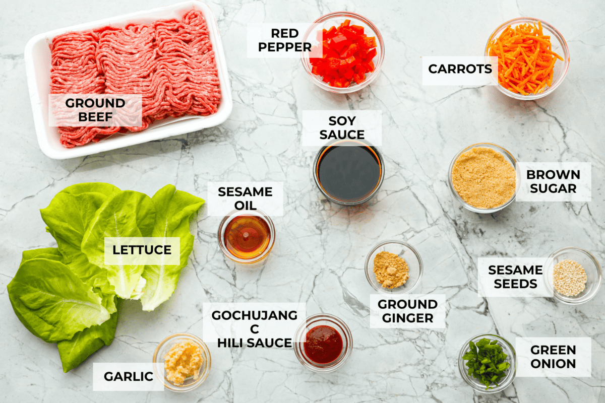 Enjoy delicious Asian flavors in these Korean Beef Lettuce Wraps! This appetizer or main is loaded with tasty lean ground beef, sautรฉed shredded carrots, red bell pepper, and garlic, all tossed in a mouthwatering sauce and spooned into lettuce leaves. Overhead shot of labeled ingredients.
