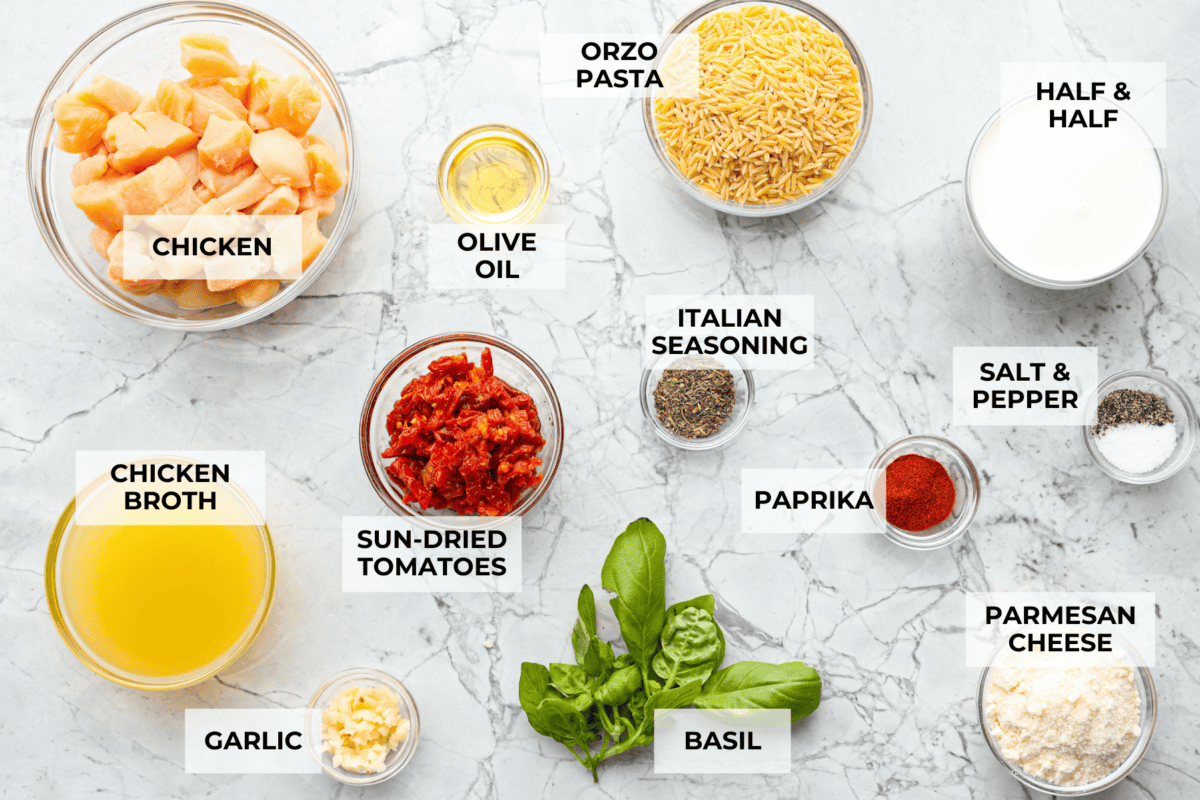 Win everyone over with One-Pan Marry Me Chicken Orzo! The recipe features tender chicken breasts cooked with orzo pasta in the most irresistible, creamy, sun-dried tomato sauce. It's quick to make and never disappoints! Overhead shot of labeled ingredients.