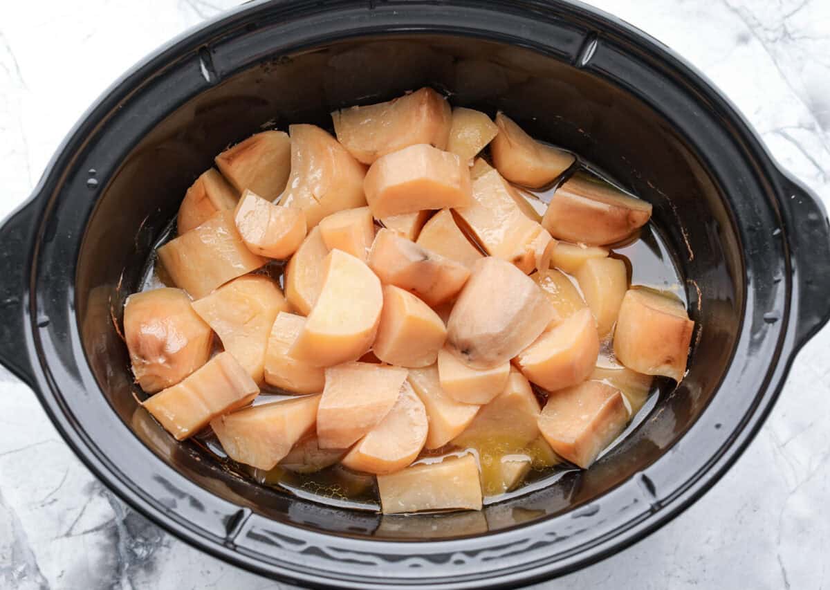 Million dollar mashed potatoes are unmatched when it comes to creamy velvety mashed potatoes. They get their intense flavors and smooth texture from letting the potatoes slow cook in chicken broth then mixing them with cream cheese, butter and garlic. Overhead shot of cooked potatoes in crockpot.