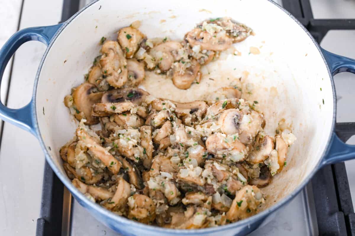Mushroom bisque is full of cream and garlic-infused mushrooms, all blended to make a thick, rich, and beyond flavorful soup! You will want to drink this straight from your bowl! Overhead shot of mushroom mixture with flour in a skillet.