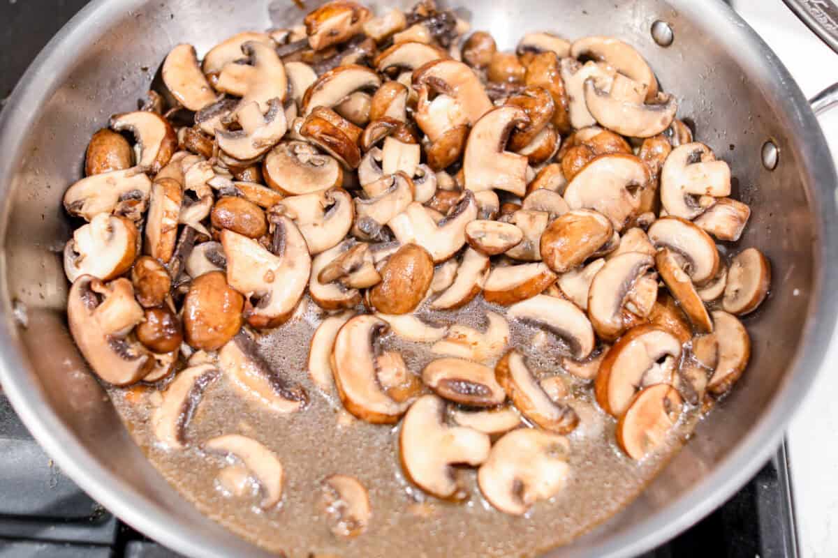 This creamy Mushroom Casserole is an impressive side dish to any meal! It's loaded with tender mushrooms mixed in a cheesy decadent sauce, then baked with a panko herb topping. First photo of mushrooms cooking in a large skillet.