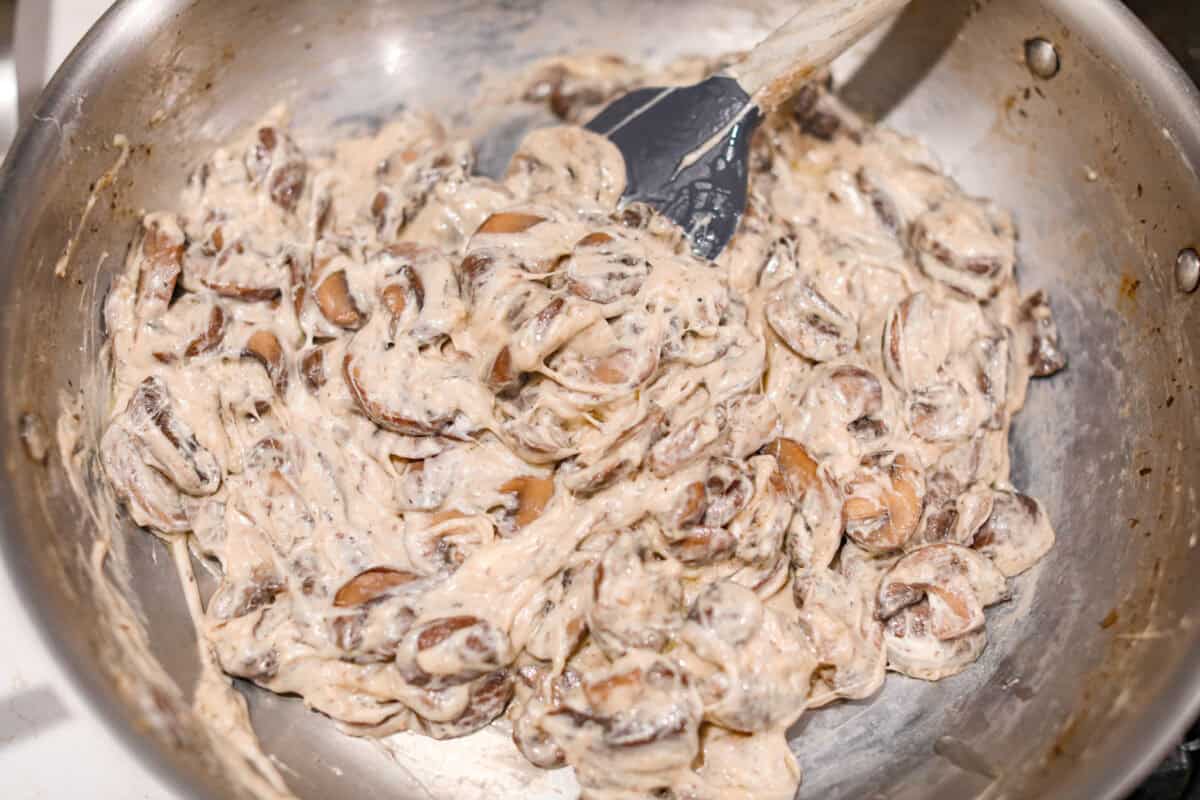 This creamy Mushroom Casserole is an impressive side dish to any meal! It's loaded with tender mushrooms mixed in a cheesy decadent sauce, then baked with a panko herb topping. Fourth photo of the mushrooms stirred into the creamy mixture.