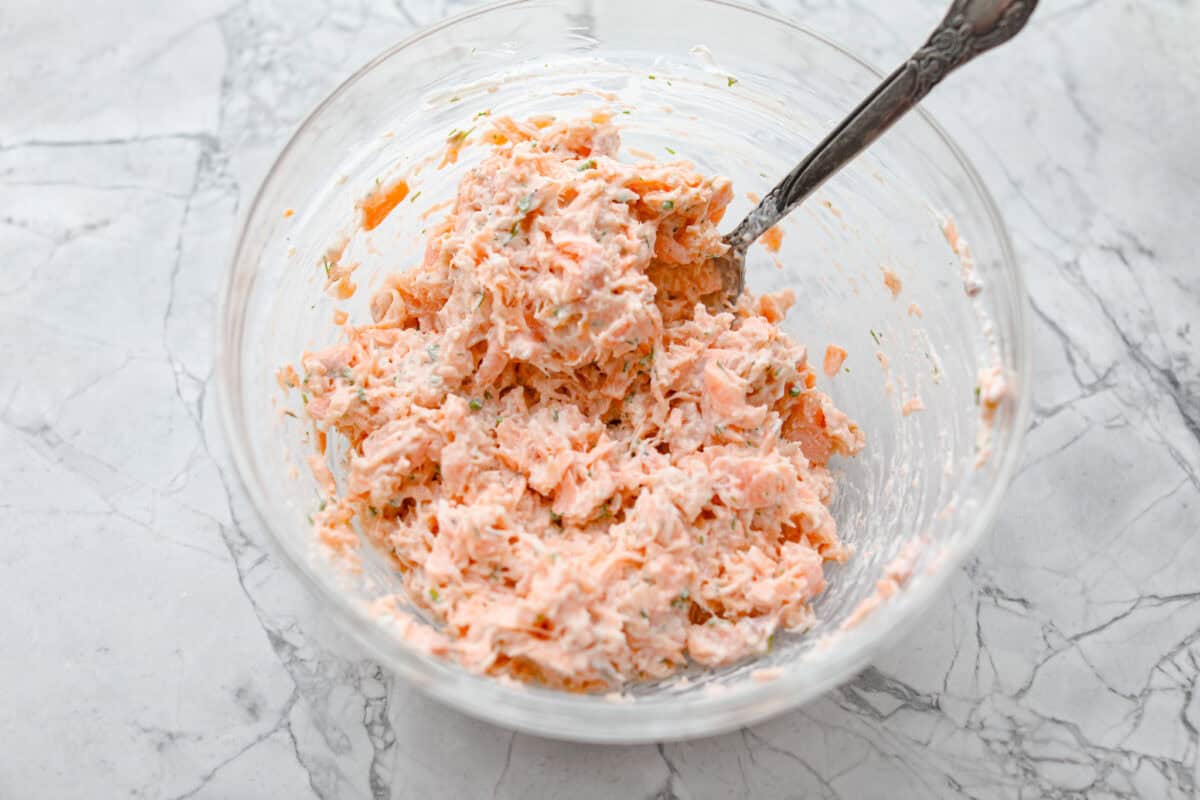 Salmon rillettes is a creamy, flavorful spread made with fresh and smoked salmon blended with lemon, sour cream, and herbs. It is perfect for spreading on crackers or toasted baguette slices. This elegant appetizer is a crowd-pleaser for any occasion! Overhead shot of all of the ingredients mixed together.