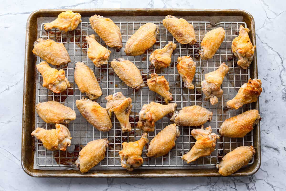 These sweet and sour wings are the perfect appetizer to serve for your next party, game day, or after-school snack. They are baked to crispy perfection and then doused in a sticky, sweet, and sour sauce. Baked wings on baking rack.
