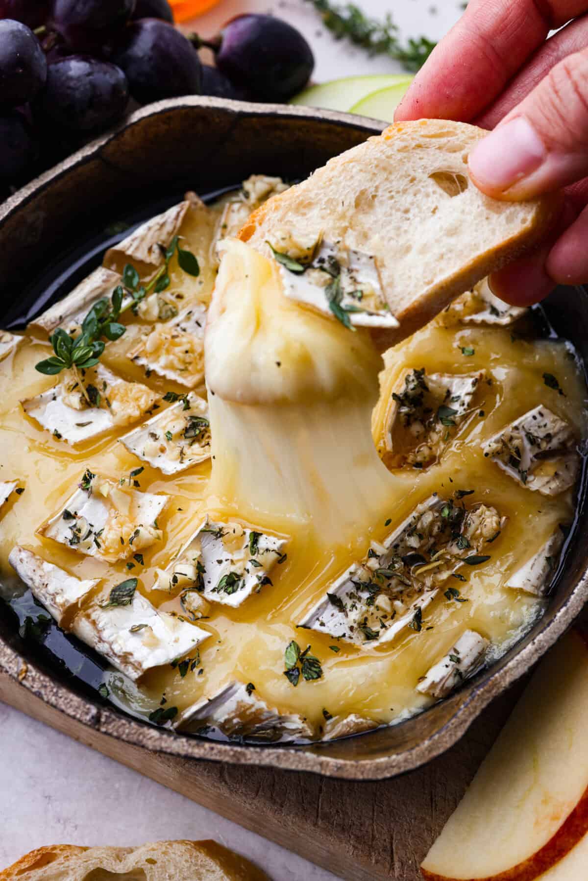 Warm and gooey baked brie is a hit for any occasion! With just five simple ingredients and less than 20 minutes, you will have a rich, creamy appetizer that's impossible to resist. Scoop it up with your favorite crackers or bread! Close up shot of someone scooping up a bite of baked brie.