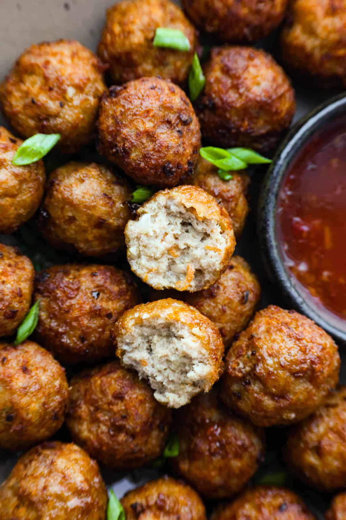 Easy Bola Bola (Filipino meatballs) combine pork, panko breadcrumbs, carrots, and onions to create a versatile meatball recipe. Tender and tasty on the inside then deep-fried and crispy on the outside! The perfect appetizer or dinner idea! Close view of the bola bola meatballs with one split open.
