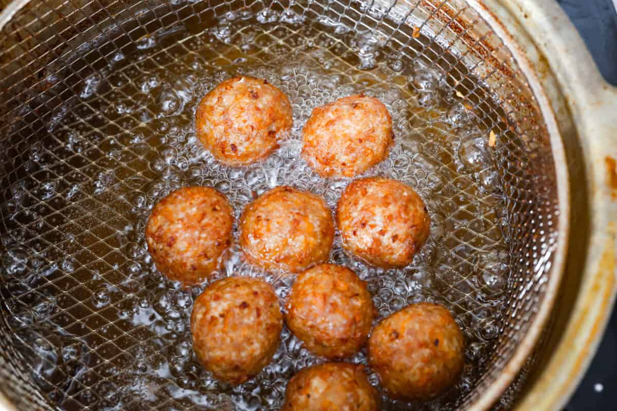 Easy Bola Bola (Filipino meatballs) combine pork, panko breadcrumbs, carrots, and onions to create a versatile meatball recipe. Tender and tasty on the inside then deep-fried and crispy on the outside! The perfect appetizer or dinner idea! Fourth photo of the bola bola meatballs frying.
