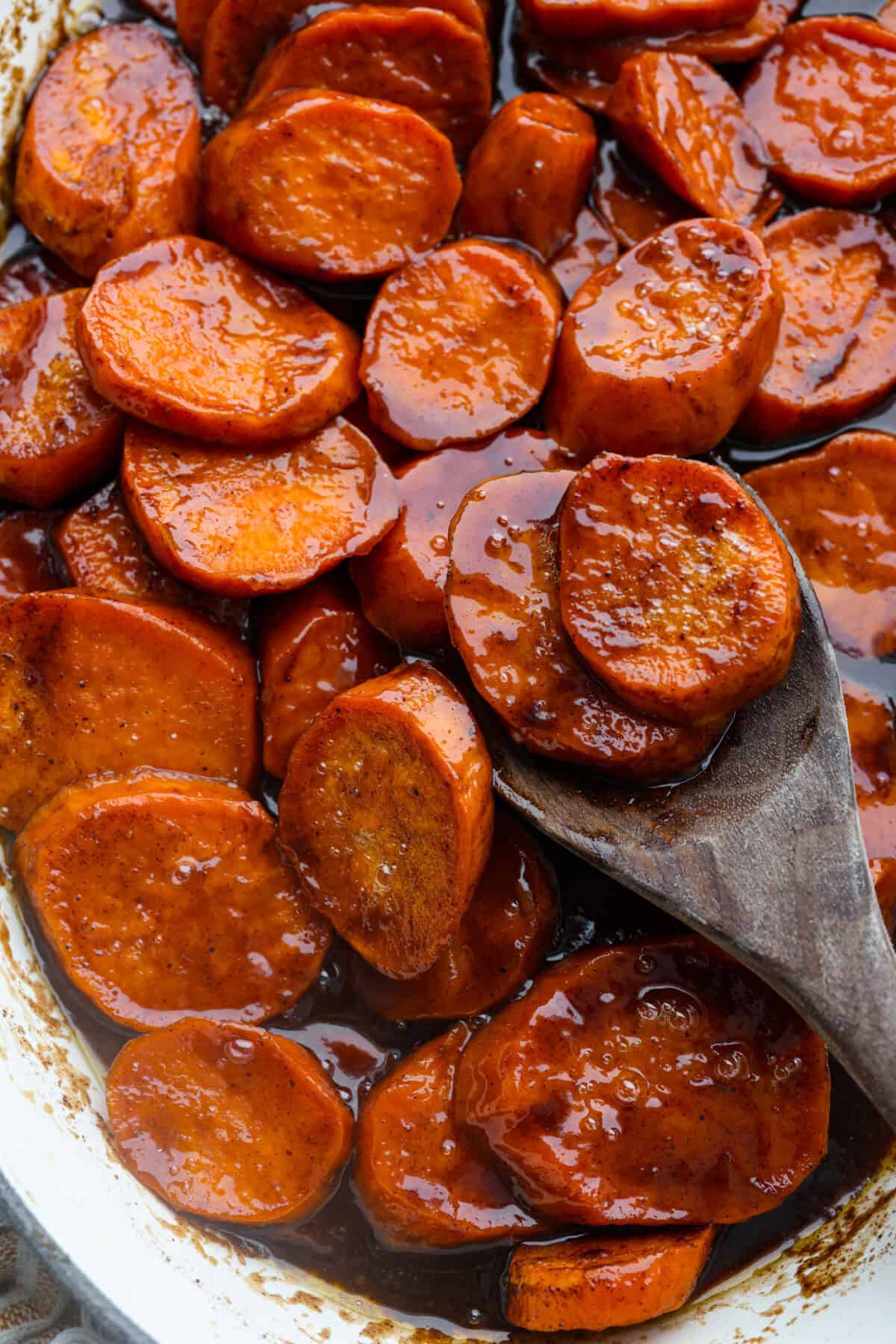 Baked candied yams are one of my favorite Thanksgiving side dishes. The succulent potato texture mixed with the sweet brown sugar spiced sauce, baked to candy perfection, tastes incredible. Close up shot of baked candied yams.