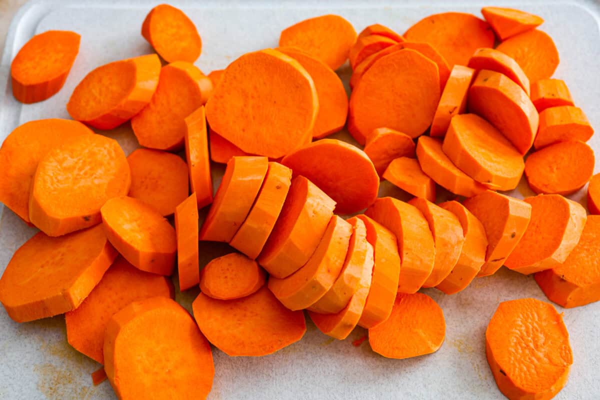 Baked candied yams are one of my favorite Thanksgiving side dishes. The succulent potato texture mixed with the sweet brown sugar spiced sauce, baked to candy perfection, tastes incredible. Overhead shot of sliced up yams on a cutting board.
