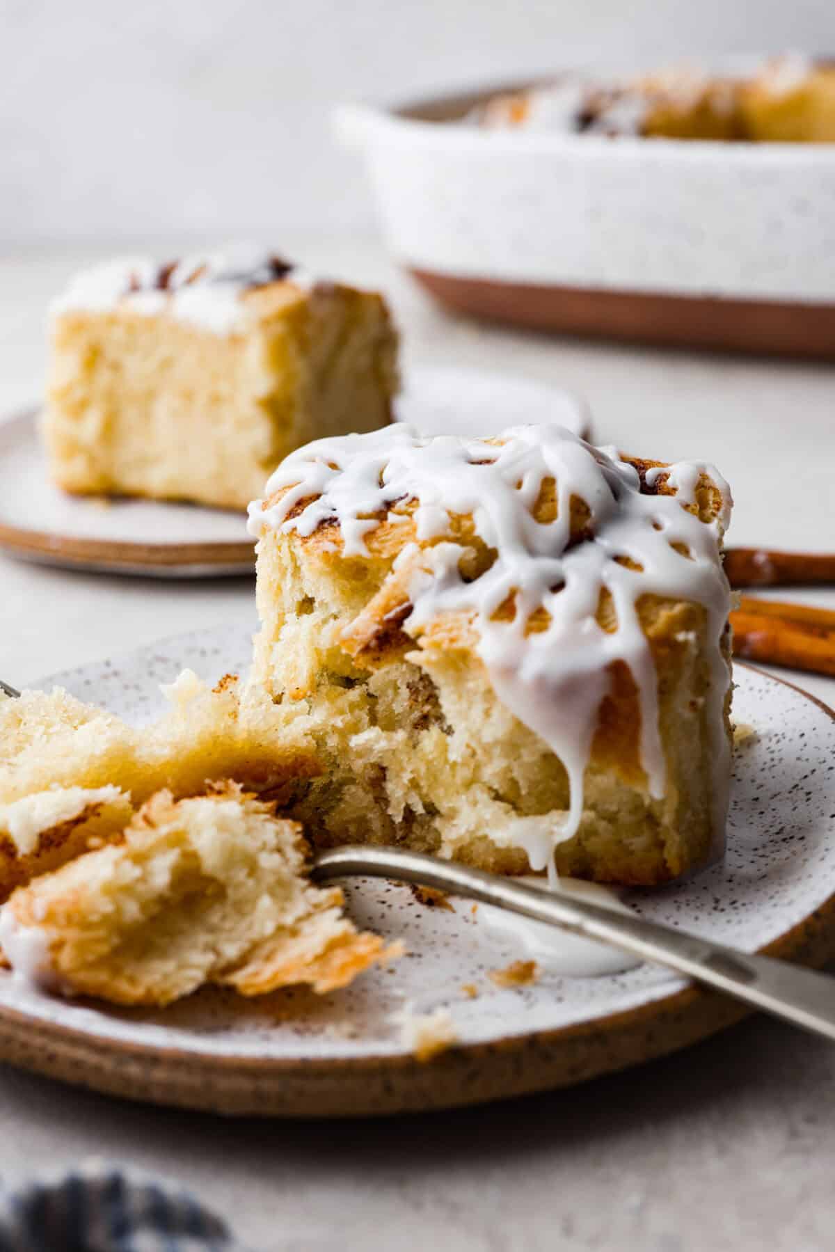 Biscuit Cinnamon Rolls are the most amazing twist on a classic! They are perfectly light, fluffy, and packed with cinnamon. The texture is more flakey and moist than traditional cinnamon rolls! Whether it’s for a cozy weekend breakfast or a holiday brunch, these hit the spot! side shot of a plated biscuit cinnamon roll cut with a fork.