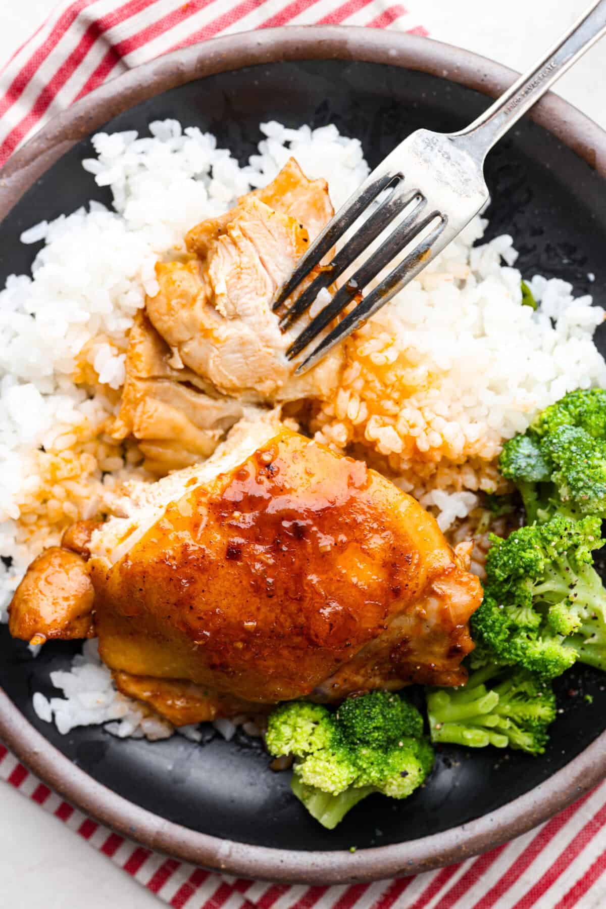 This incredibly tasty Coca-Cola chicken thigh recipe can be on the table in 40 minutes. The succulent sauce is a combination of savory soy sauce, Worcestershire, garlic, ketchup, and, of course, Coca-Cola. You've never had more flavorful chicken thighs than these! Overhead shot of plated coca-cola chicken thighs over rice and brocolli.