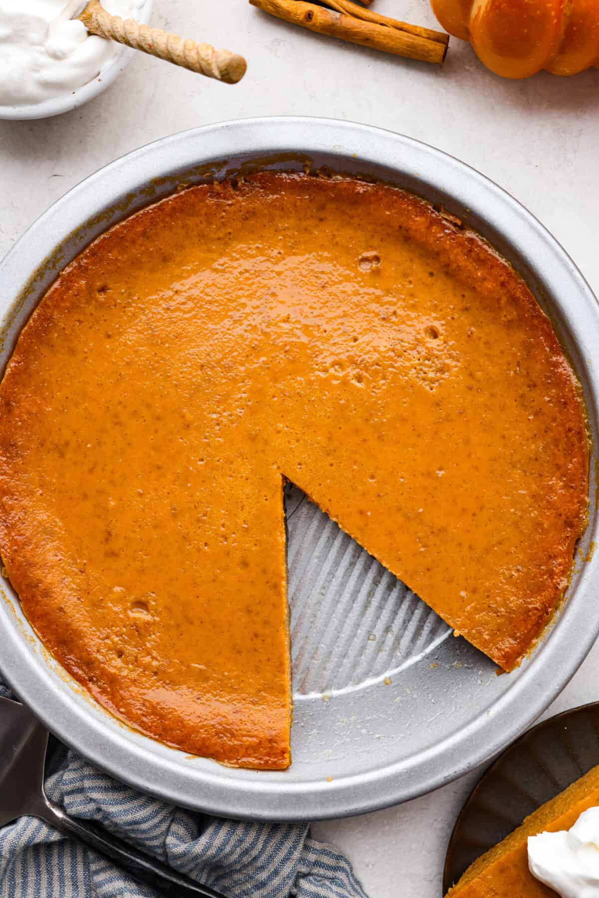 Crustless pumpkin pie has rich spices, creamy pumpkin, and a perfectly smooth texture. The custard holds its shape beautifully. Whether you're keeping things simple or exploring a gluten-free option, this pie gives all the nostalgic vibes of the classic. Overhead shot of a crustless pumpkin pie with a slice taken out.