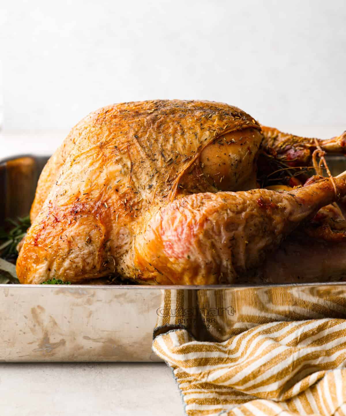 When you dry brine your turkey, you end up with a beautifully browned bird with crispy skin on the outside and juicy, flavorful meat on the inside! It will for sure be one of the most flavorful, moist turkeys you've ever had! Side shot of dry brine turkey in a pan.