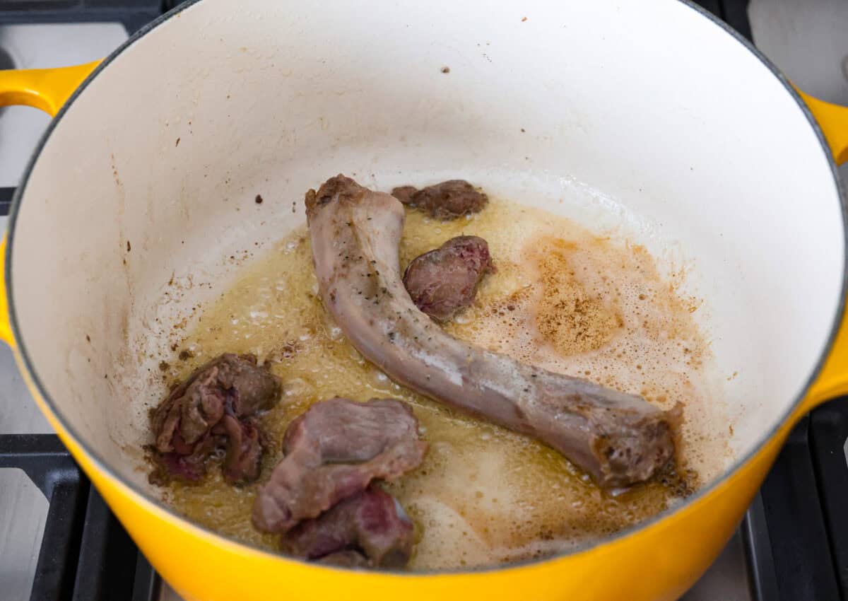 Giblet gravy is a labor of love, but the flavor is unmatched! Using the turkey's neck, gizzard, heart, liver, and drippings, you can make the best gravy you've ever had! It will be the perfect complement to your holiday turkey dinner. Angle shot of giblets cooking in melted butter in a pan.