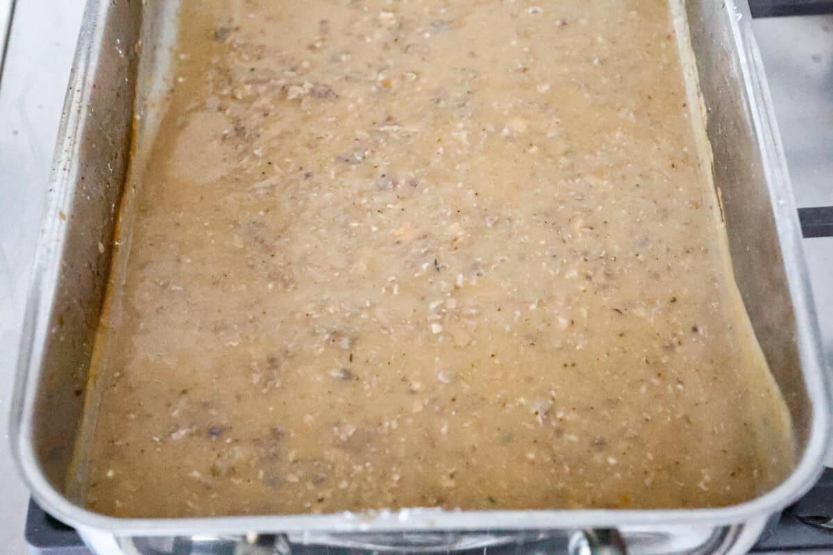 Giblet gravy is a labor of love, but the flavor is unmatched! Using the turkey's neck, gizzard, heart, liver, and drippings, you can make the best gravy you've ever had! It will be the perfect complement to your holiday turkey dinner. Overhead shot of giblet gravy being heated up in the turkey pan.