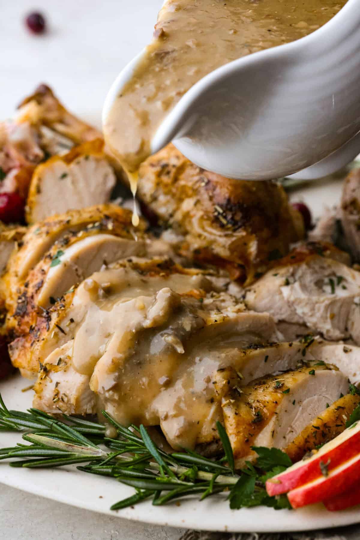 Giblet gravy is a labor of love, but the flavor is unmatched! Using the turkey's neck, gizzard, heart, liver, and drippings, you can make the best gravy you've ever had! It will be the perfect complement to your holiday turkey dinner. Side shot of someone pouring giblet gravy onto sliced turkey breast on a plate.