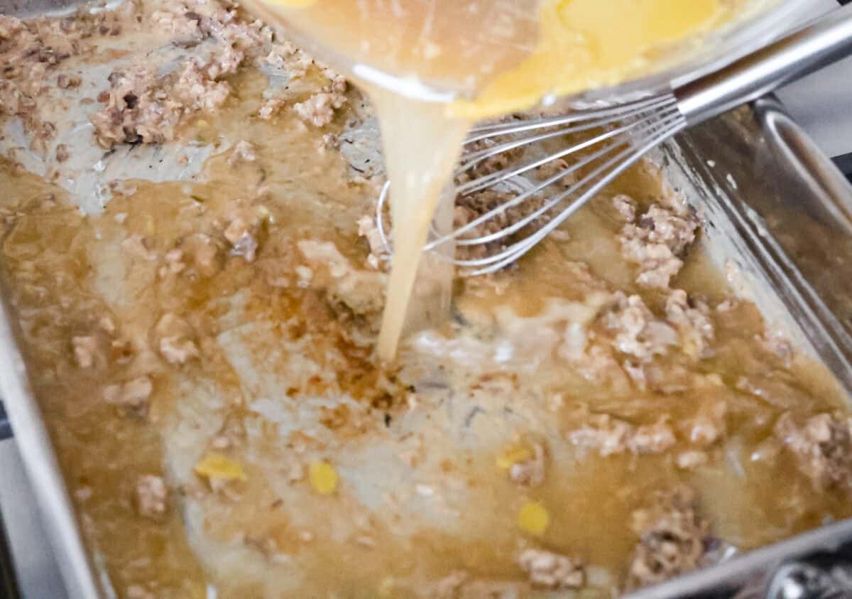 Giblet gravy is a labor of love, but the flavor is unmatched! Using the turkey's neck, gizzard, heart, liver, and drippings, you can make the best gravy you've ever had! It will be the perfect complement to your holiday turkey dinner. Angle shot of someone pouring the remaining giblet broth into the pan with the giblets, flour and turkey drippings.