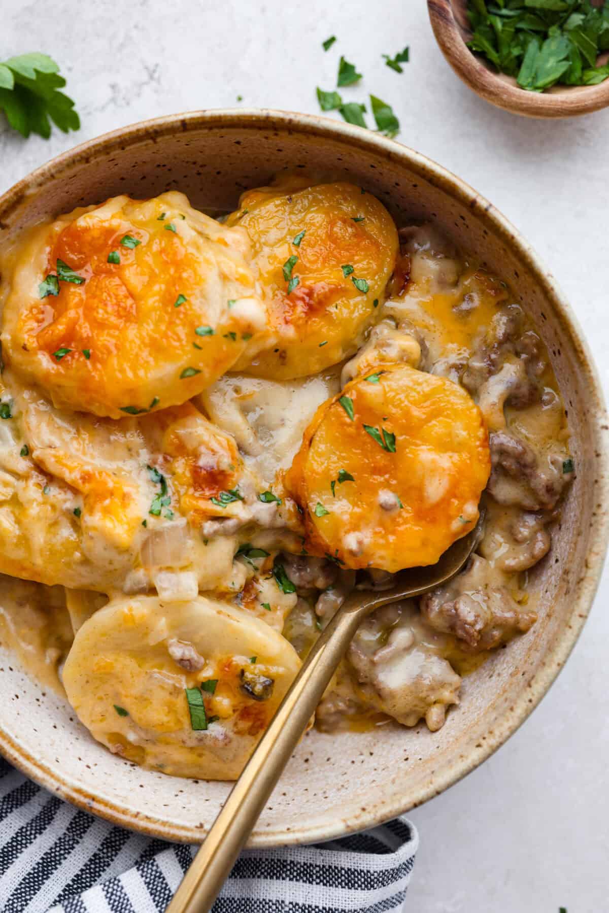 Hamburger Potato Casserole is hearty, filling, and great for family dinners. It's full of tender potatoes and ground beef, smothered in a deliciously creamy sauce, and covered in melty cheese. Overhead shot of plated hamburger potato casserole.