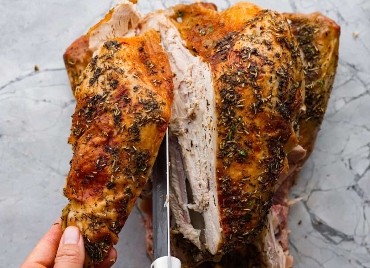 Learning how to carve a turkey is easier than you think! My step-by-step tutorial is here to help you along the way. Impress your guests with your beautifully carved turkey. Fifth photo of the knife cutting the breast completely off the bird.