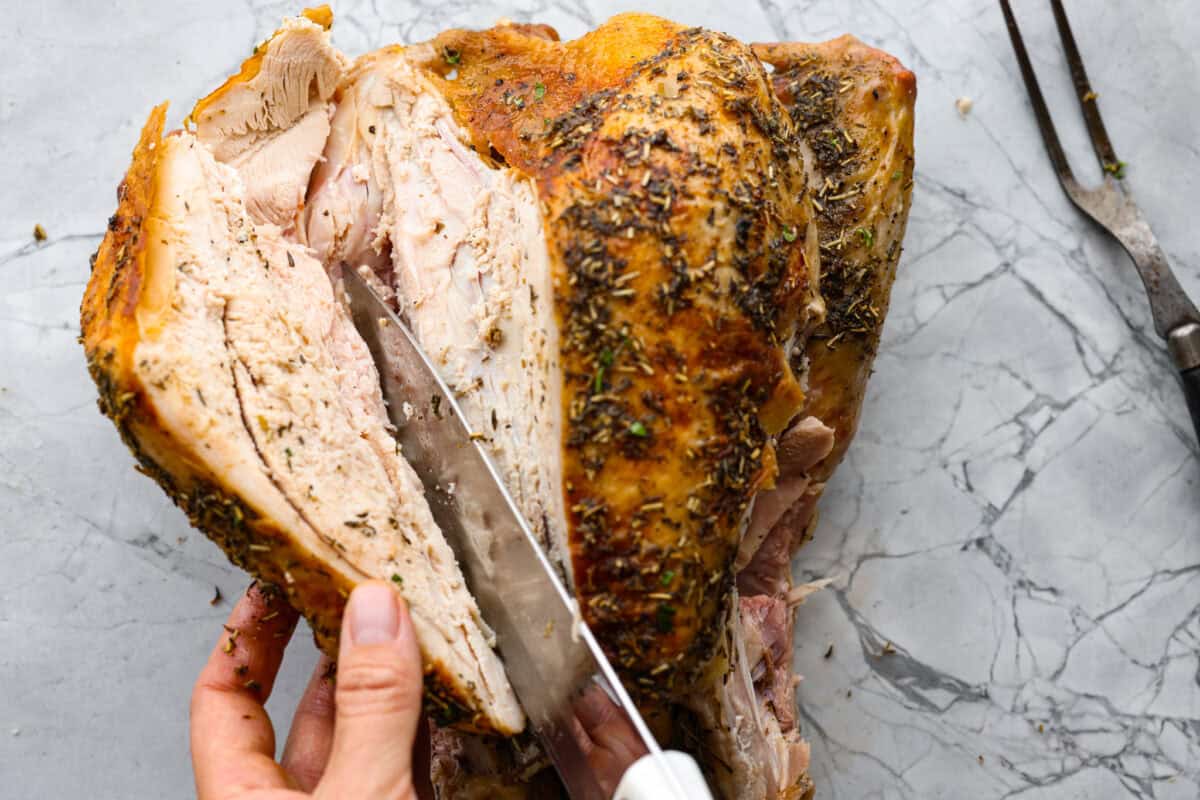 Learning how to carve a turkey is easier than you think! My step-by-step tutorial is here to help you along the way. Impress your guests with your beautifully carved turkey. Fourth photo of the knife cutting along the curve of the bone.