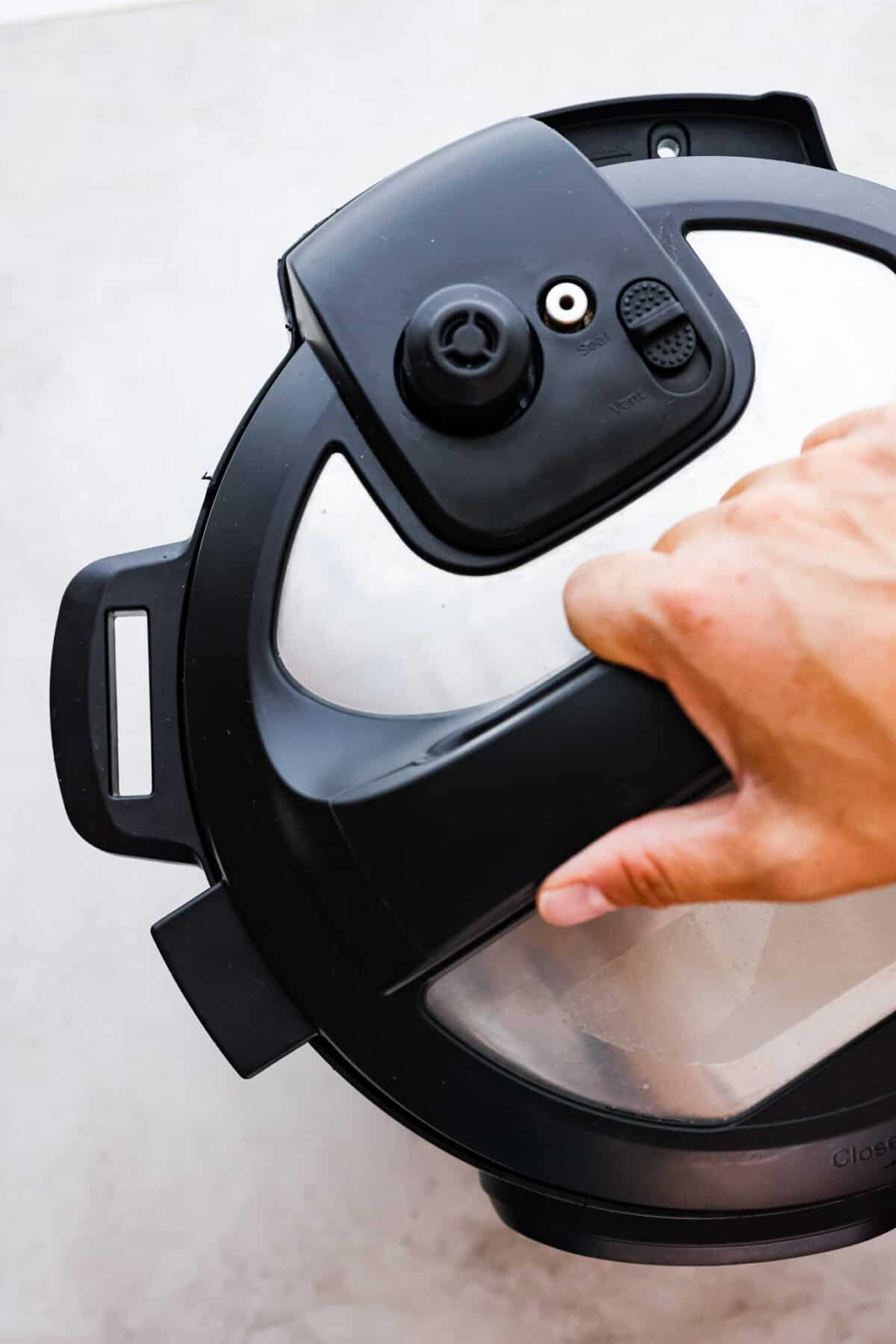 STOP being scared of your Instant Pot! This beginner's guide on How to Use an Instant Pot will help you feel comfortable and confident when using this magical kitchen appliance. It makes cooking fast, easy, and convenient. First photo of a top view of placing the lid on the Instant pot.