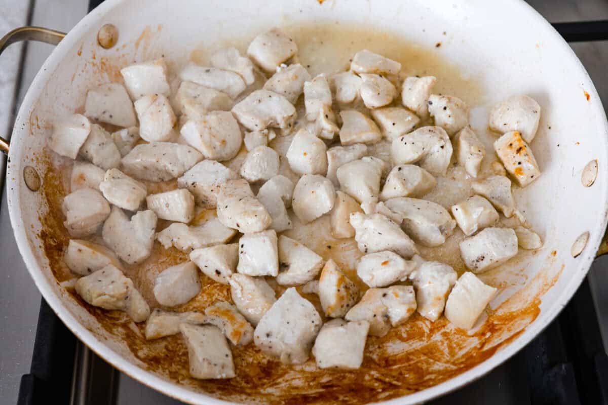 Win everyone over with One-Pan Marry Me Chicken Orzo! The recipe features tender chicken breasts cooked with orzo pasta in the most irresistible, creamy, sun-dried tomato sauce. It's quick to make and never disappoints! Overhead shot of chicken cooking in a skillet.