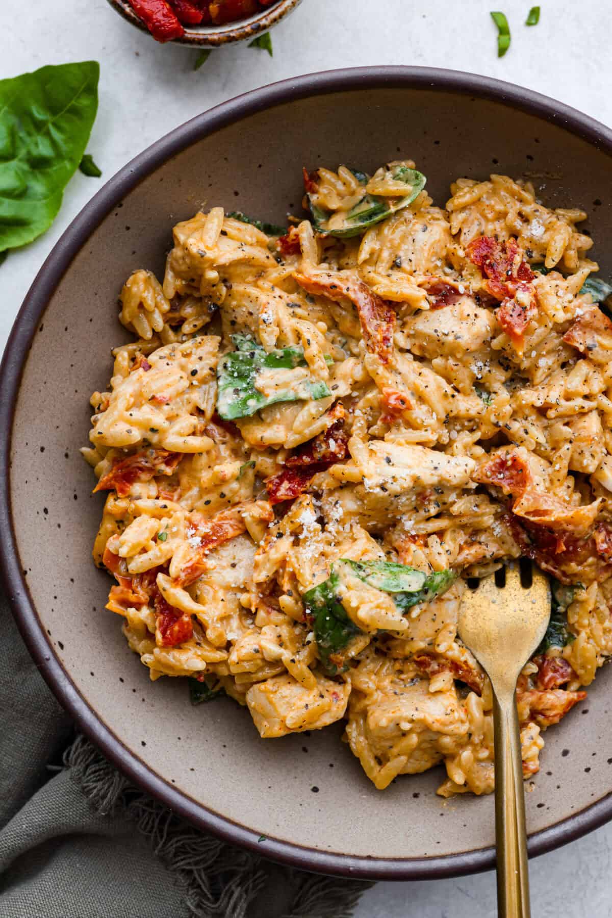 Win everyone over with One-Pan Marry Me Chicken Orzo! The recipe features tender chicken breasts cooked with orzo pasta in the most irresistible, creamy, sun-dried tomato sauce. It's quick to make and never disappoints! Overhead shot of plated marry me chicken orzo.