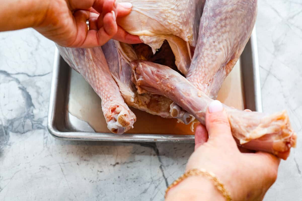 When you dry brine your turkey, you end up with a beautifully browned bird with crispy skin on the outside and juicy, flavorful meat on the inside! It will for sure be one of the most flavorful, moist turkeys you've ever had! Overhead shot of someone prepping the turkey by taking the giblets out.