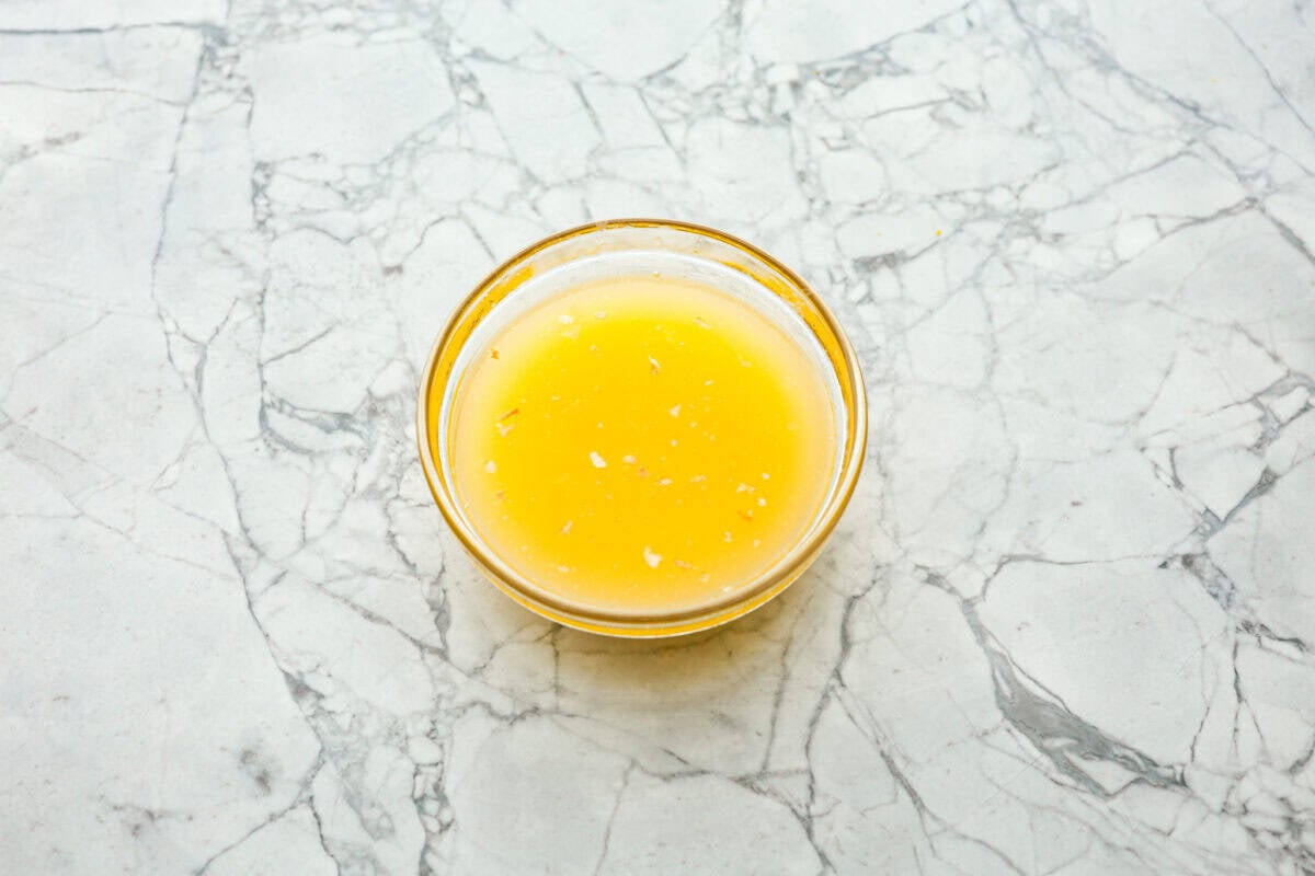 Philly cheesesteak sliders are a fun and delicious twist on a classic. These Philly cheesesteaks are filled with thinly sliced steak, caramelized onions, crisp peppers, and, of course, melty cheese. Overhead shot of melted butter and seasonings in a small glass bowl.