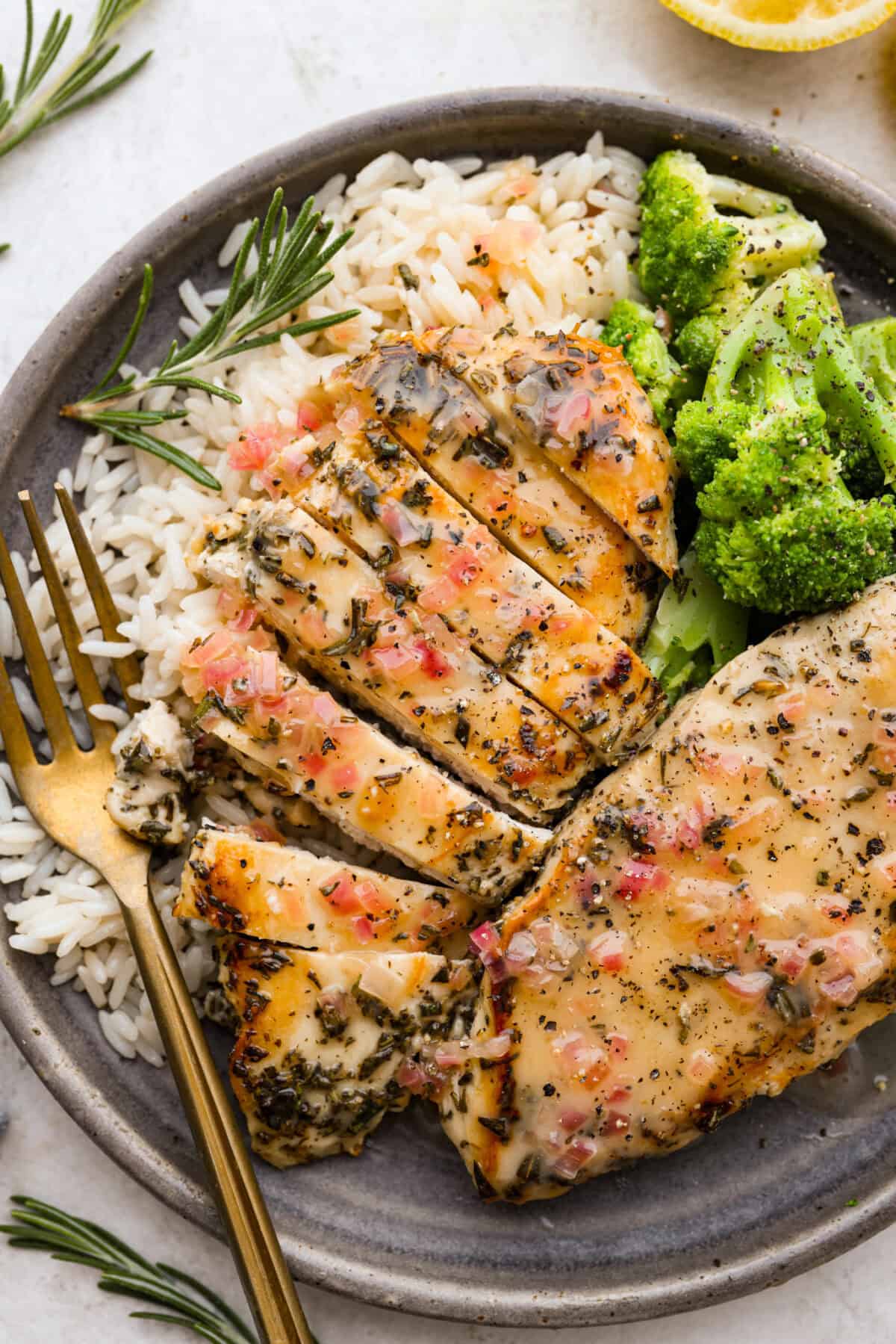 Rosemary Chicken is an incredibly simple yet flavorful dish you can whip up in no time. The infusion of butter with savory shallots, bright lemon juice, fresh rosemary, and tender seared chicken is an explosion of flavor. Overhead shot of plated rosemary chicken on a plate with rice and broccoli.