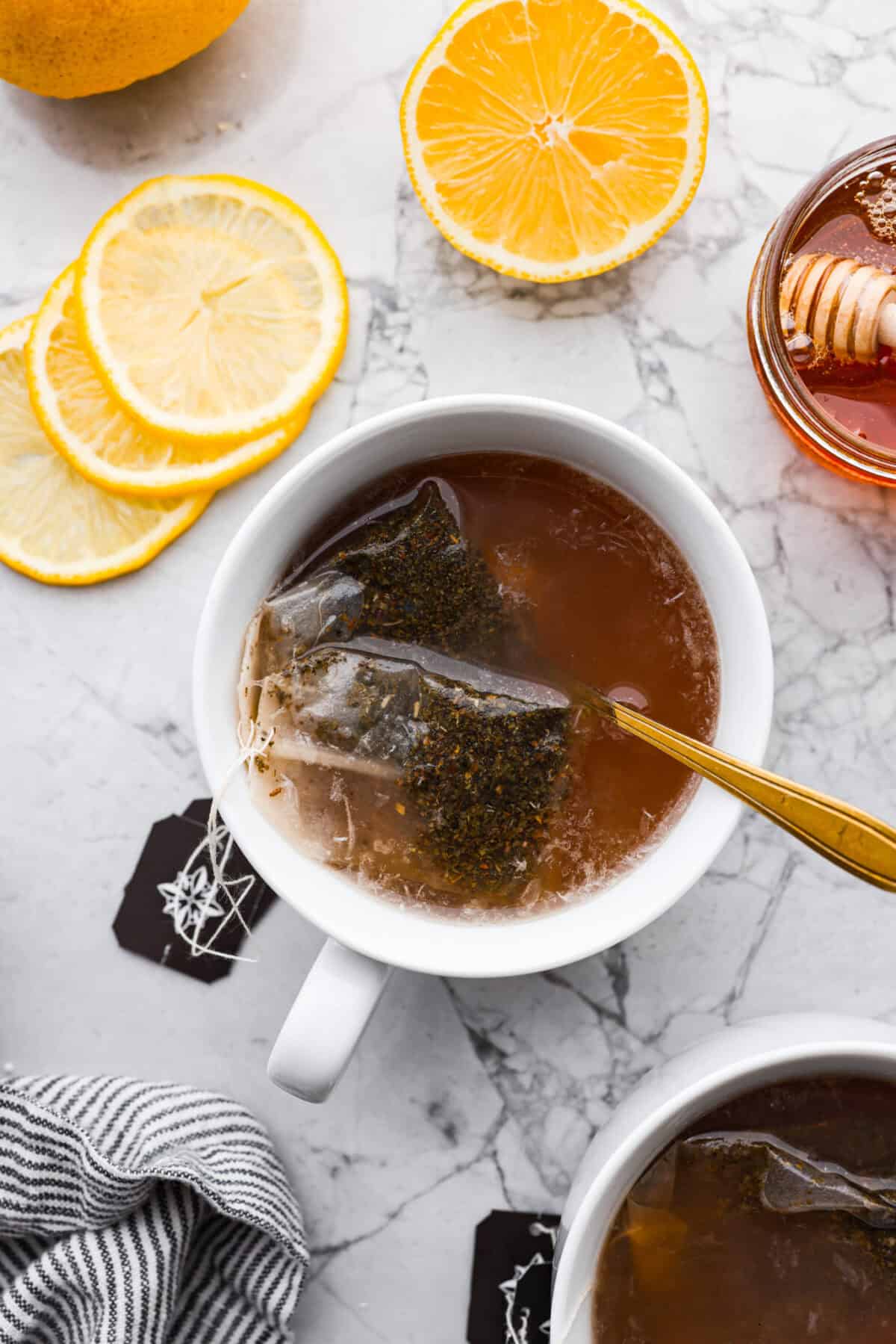 Whenever I am sick, the Starbucks Medicine Ball is my go-to, and this homemade version is even better! Perfect for cold and flu season, this warm drink made of lemonade, honey, and tea is soothing and delicious! Overhead shot of copycat Starbucks medicine ball tea in a mug.