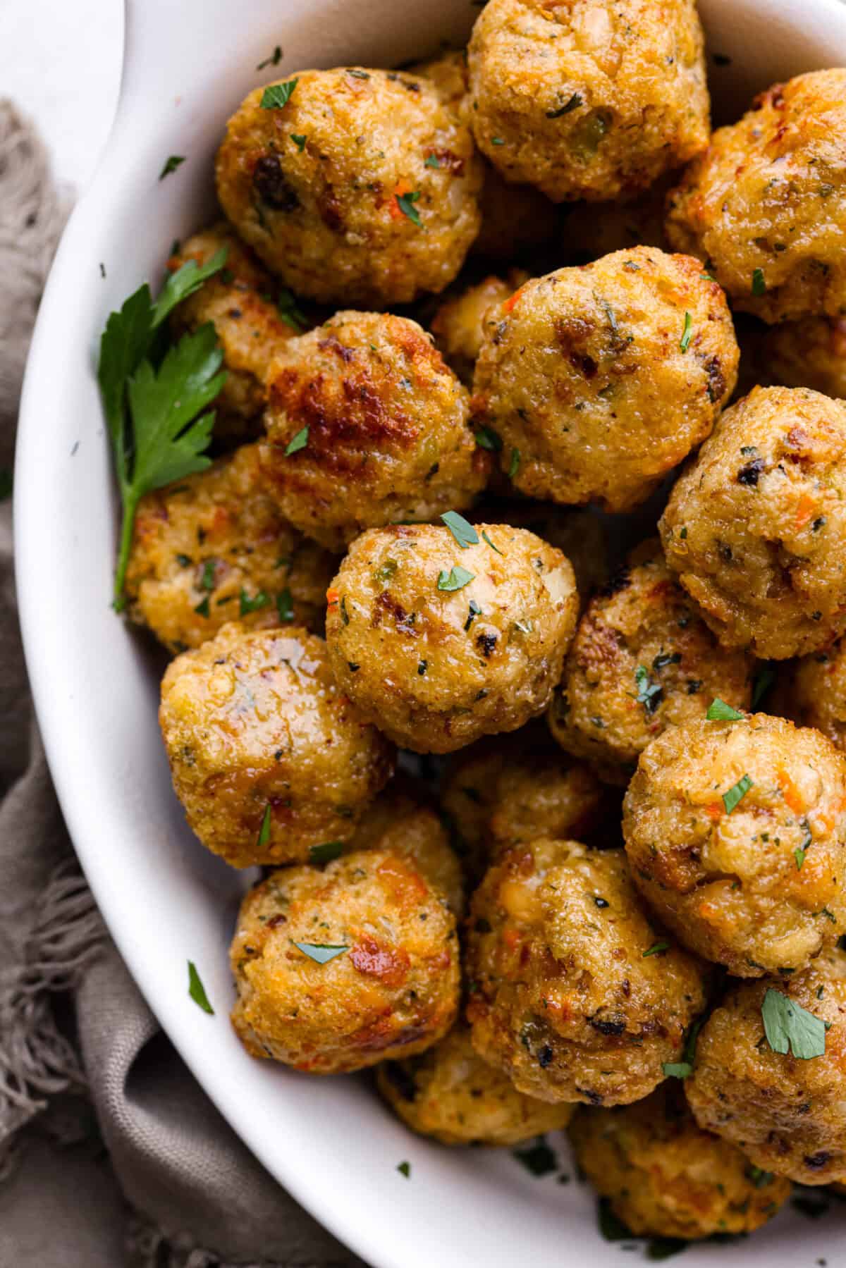 Turkey Stuffing Balls capture the taste of Thanksgiving in a single bite! Made with tender turkey, flavorful stuffing, and mashed potatoes. Theyโre rolled into perfectly poppable bites and served with rich gravy for dipping. Close up shot of a bowl of turkey stuffing meatballs.