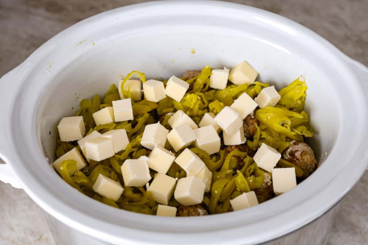 Crockpot Mississippi meatballs make the best little appetizer or side dish. The flavorful pepperoncini mixed with the au jus and ranch seasoning packets with delectable butter makes the most amazing sauce. It's perfectly soaked up by the tender meatballs. Angle shot cubed butter on tope of the peppers and seasoned meatballs.