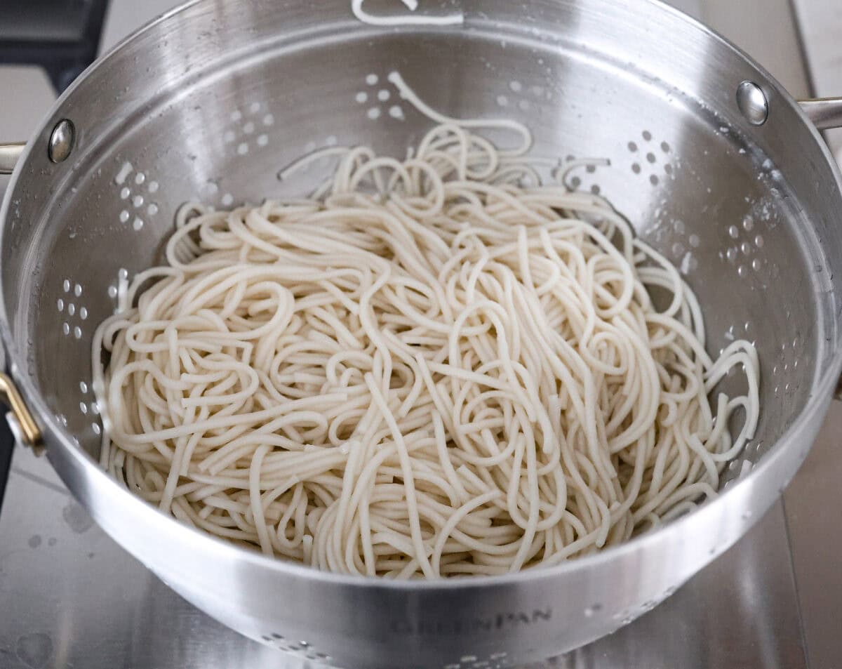 Mongolian Ground Beef and Noodles is a flavorful dinner that’s ready in 30 minutes! This dish combines tender noodles, savory ground beef, and a sweet and tangy Asian-inspired sauce for a meal that’s as comforting as it is delicious! Angle shot of cooked noodles in a colander.