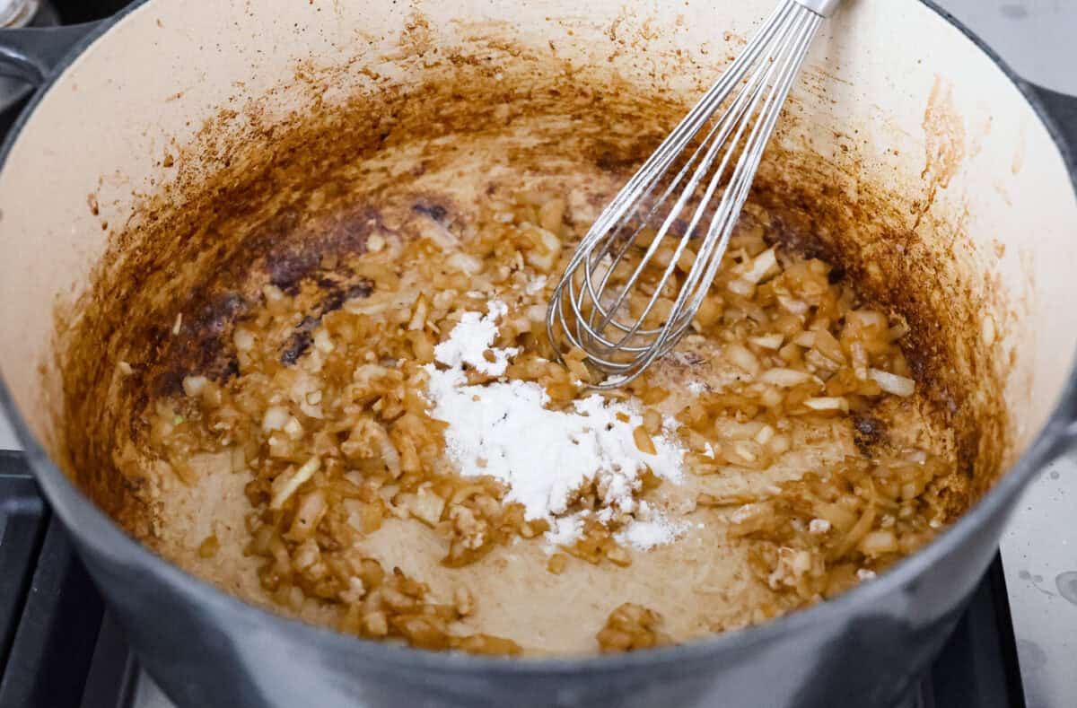 Chicken cordon bleu pasta is a creamy, flavorful dish that's a fun twist on the classic. It combines savory ham, tender chicken, melty cheese, and delicious seasonings. Easy to make and sure to please! Angle shot of flour, butter and onion in a pot.