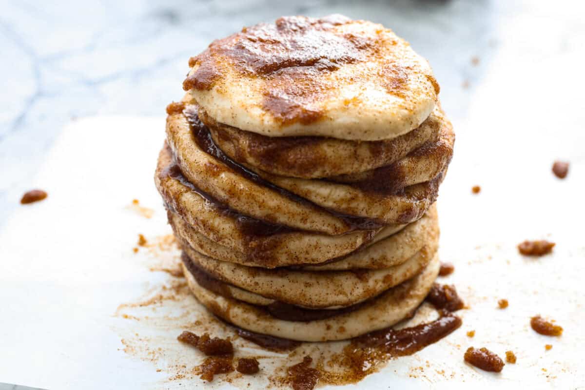 Irresistible Cinnamon Pull-Apart Bread is inspired by the popular cinnamon bread served at the Grist Mill eatery in Dollywood. With this copycat version, you can recreate that buttery, sweet deliciousness easily with frozen rolls. Angle shot of a stack of flattened dough balls that are drenched in butter, cinnamon and sugar.