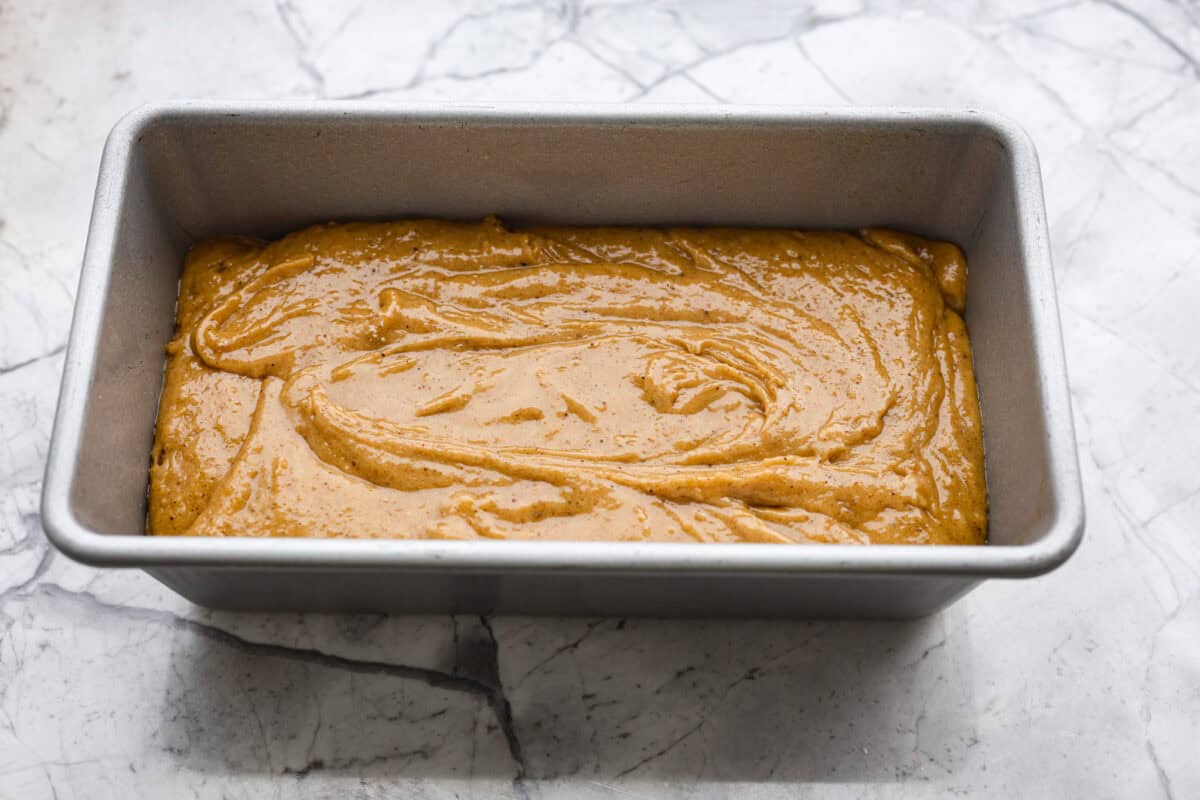 Starbucks copycat gingerbread loaf is the ultimate holiday treat! It's coated in a simple cream cheese frosting and is full of warm spices and rich molasses flavor. Enjoy it for Christmas brunch or a sweet treat at night! Overhead shot of gingerbread loaf batter in a loaf pan.
